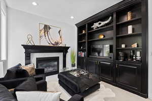 Carpeted living area with a tile fireplace, recessed lighting, and built in features