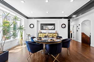 Dining room with arched walkways, wood finished floors, ornamental molding, recessed lighting, and a textured ceiling