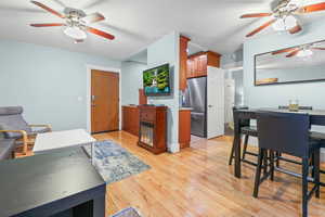 Kitchen with ceiling fan, freestanding refrigerator, light wood finished floors, and wood finish cabinetry