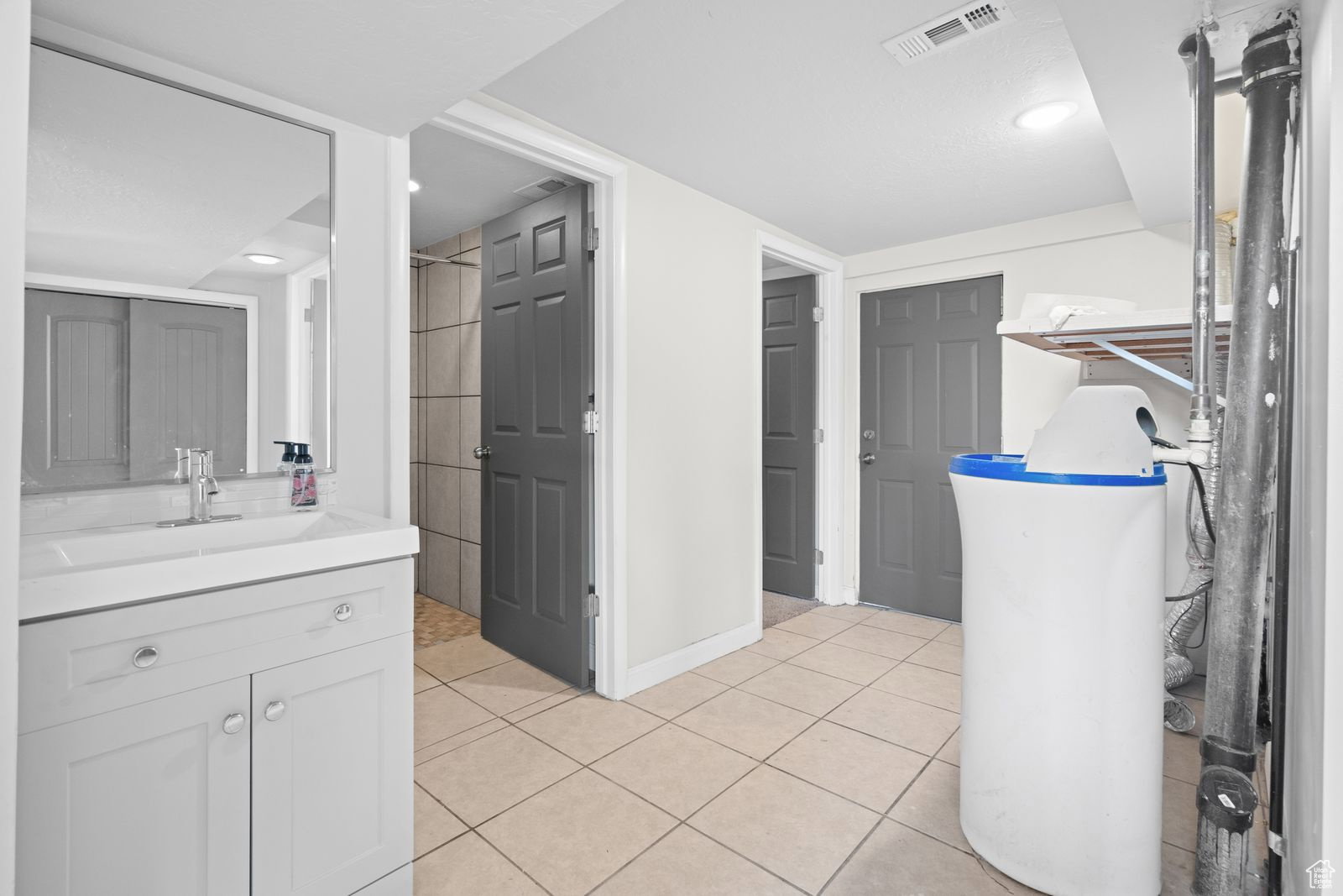 Full bathroom with vanity, light tile patterned floors, a closet, and a shower