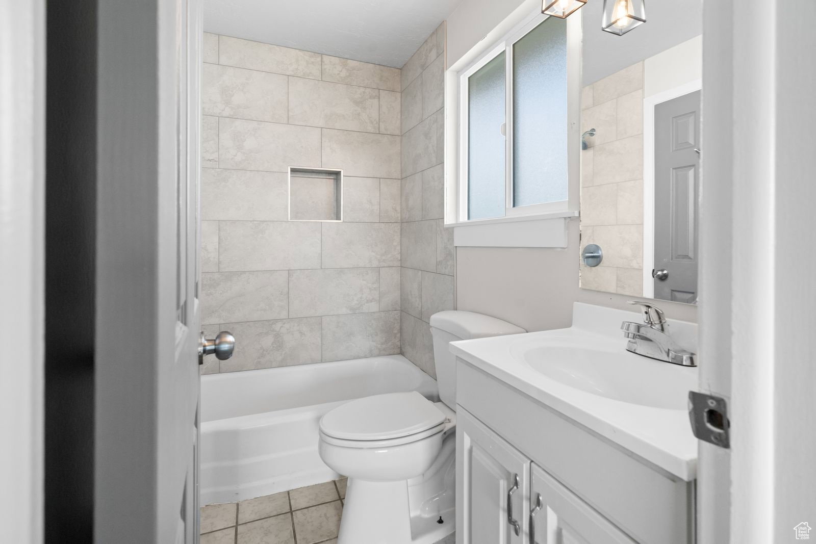 Bathroom with vanity, light tile patterned flooring, and shower / tub combination