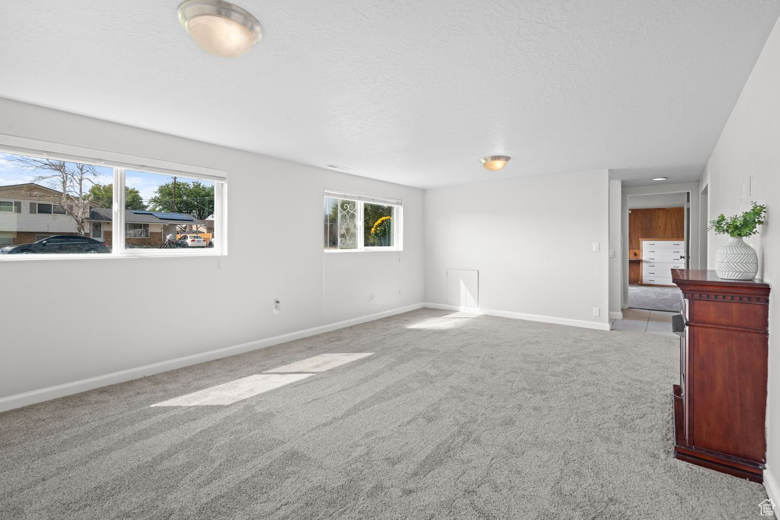 Empty room featuring light colored carpet and a textured ceiling