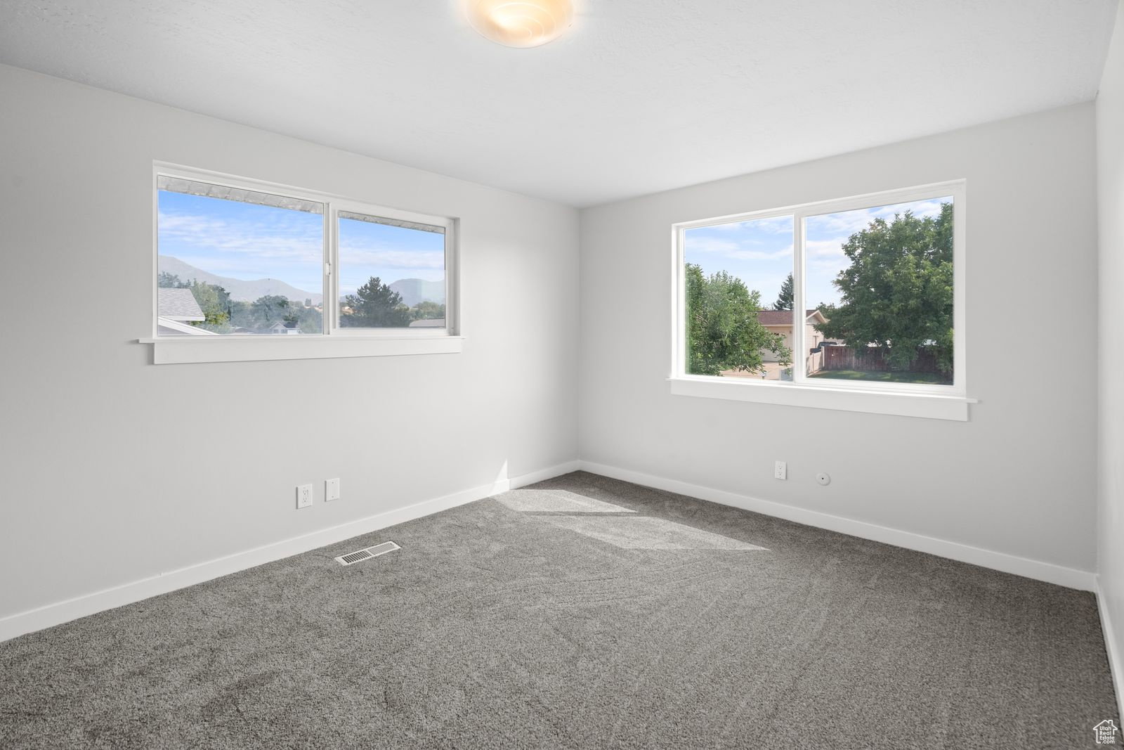 Carpeted spare room featuring healthy amount of natural light