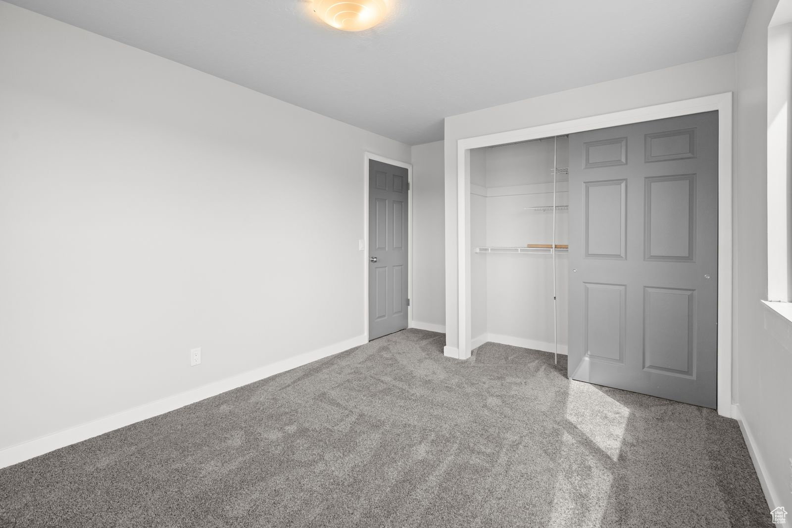 Unfurnished bedroom with light colored carpet and a closet