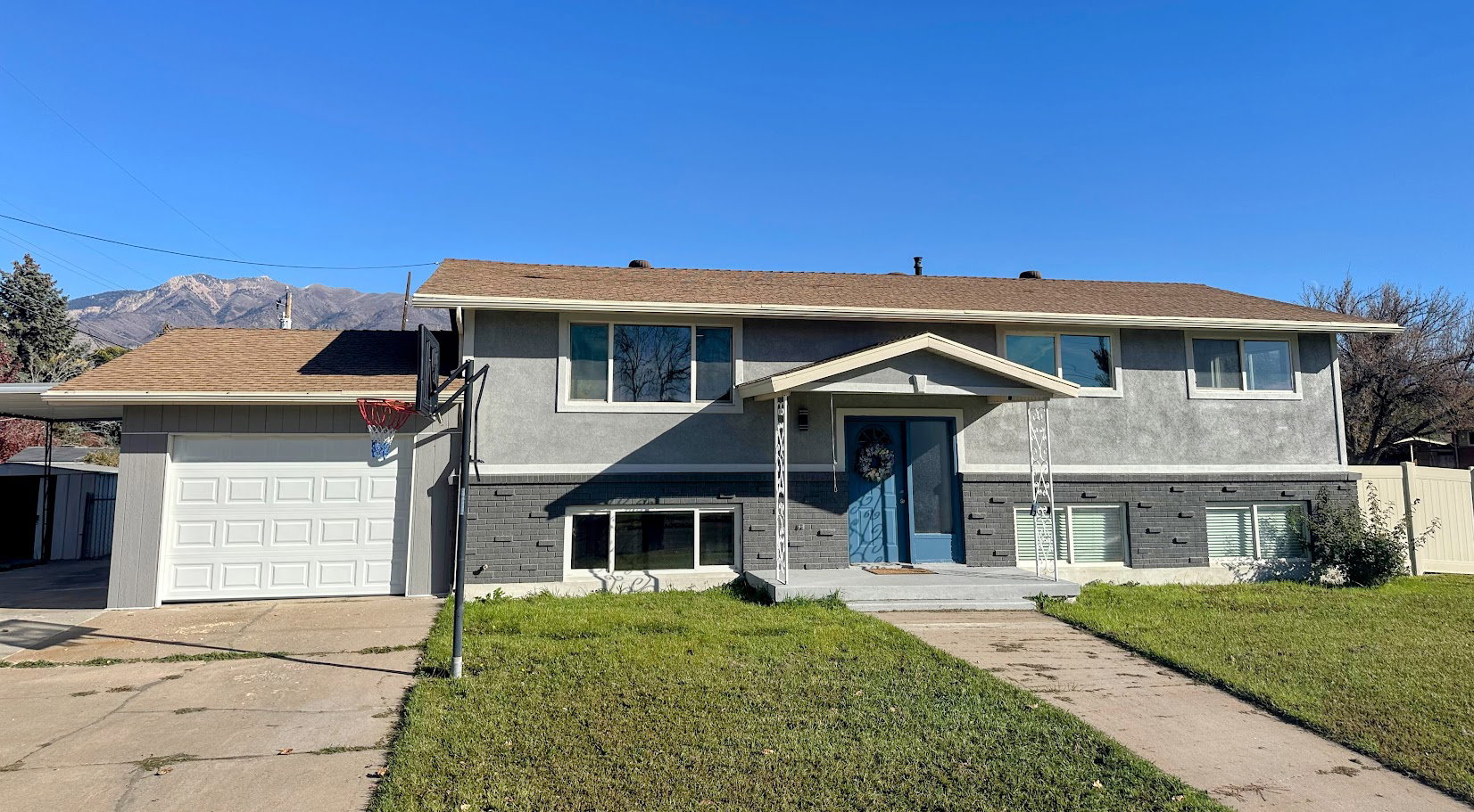 Bi-level home with brick siding, stucco siding, a front yard, concrete driveway, and a garage