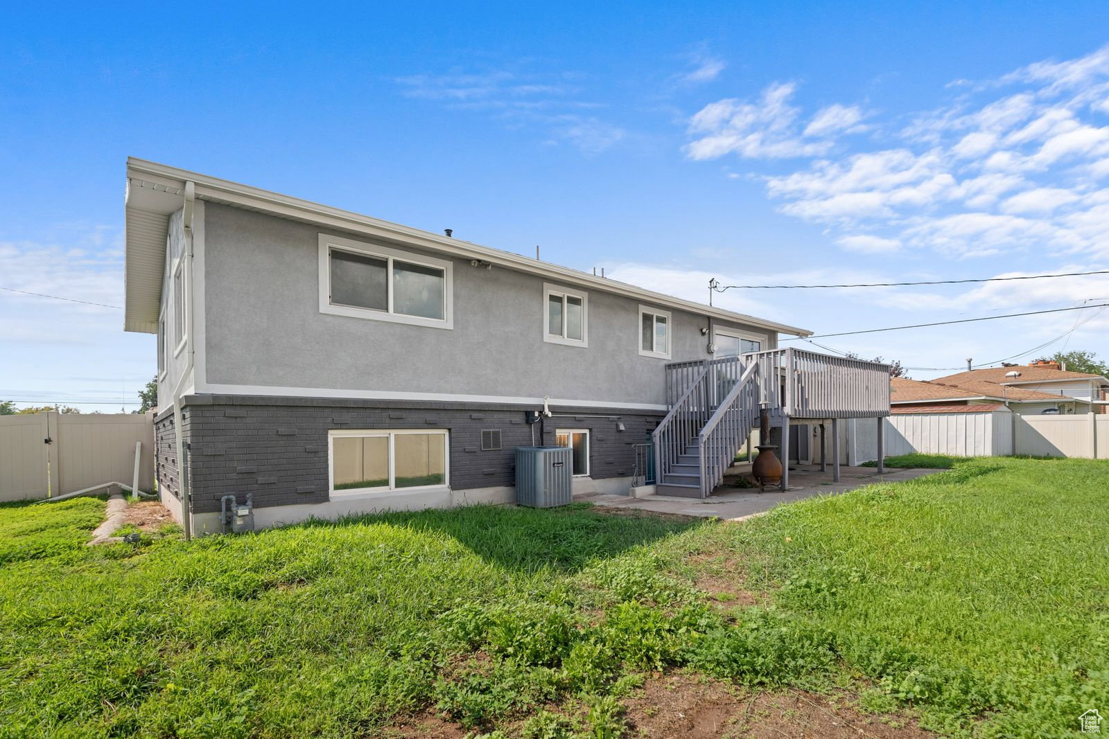 Back of property with a fenced backyard, stucco siding, brick siding, a wooden deck, and a gate