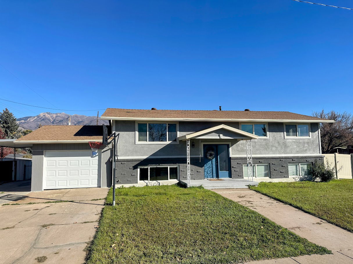 Raised ranch with brick siding, stucco siding, driveway, an attached garage, and a mountain view