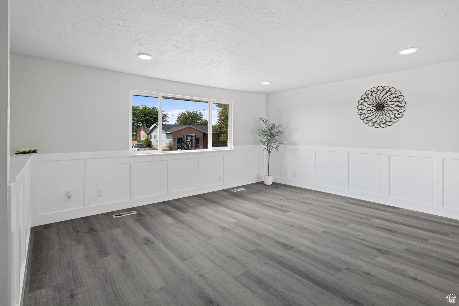 Spare room featuring a wainscoted wall, a decorative wall, and light wood-style floors