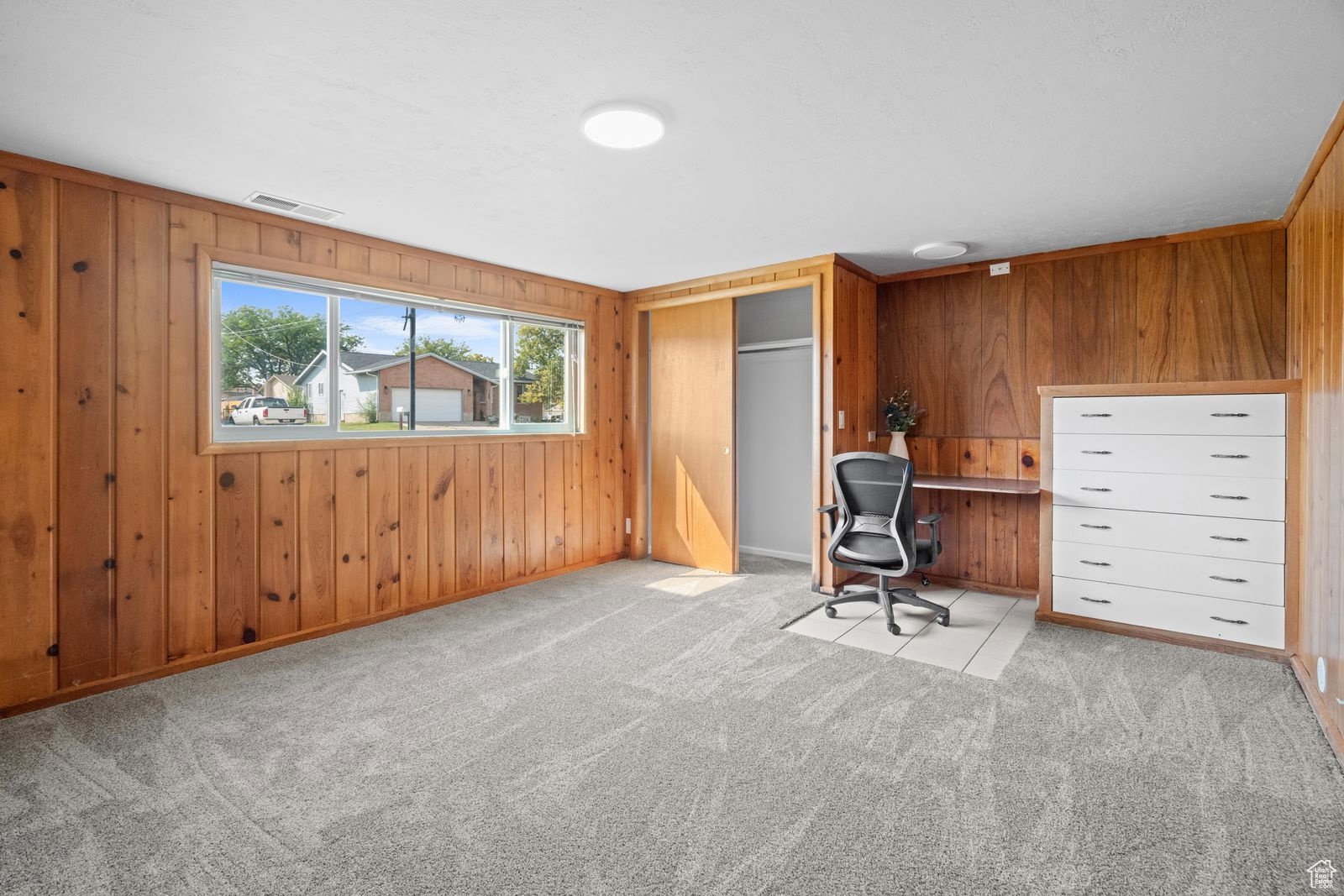 Home office with wood walls and light colored carpet