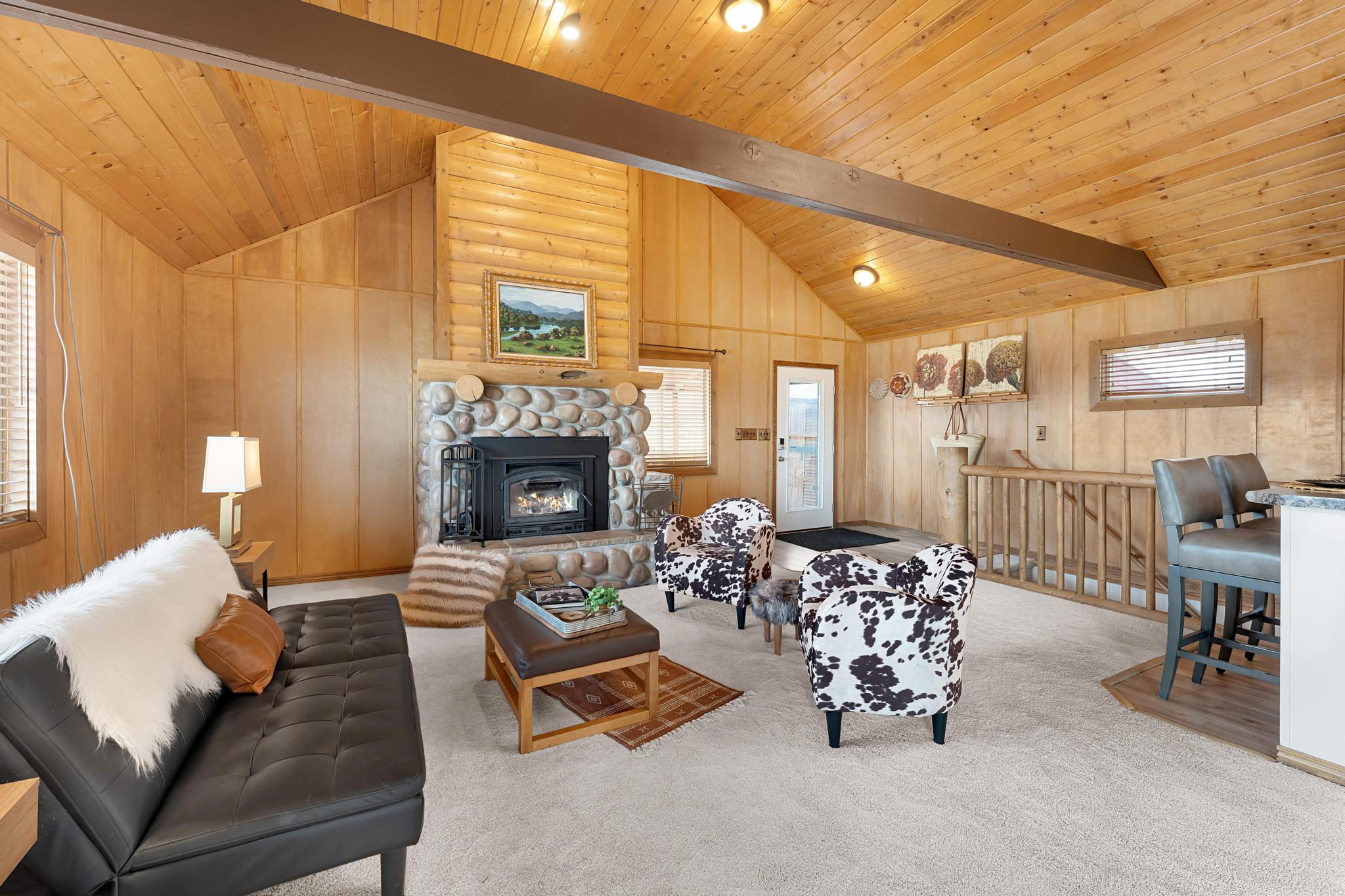 Carpeted living area featuring a fireplace, wooden walls, and vaulted ceiling