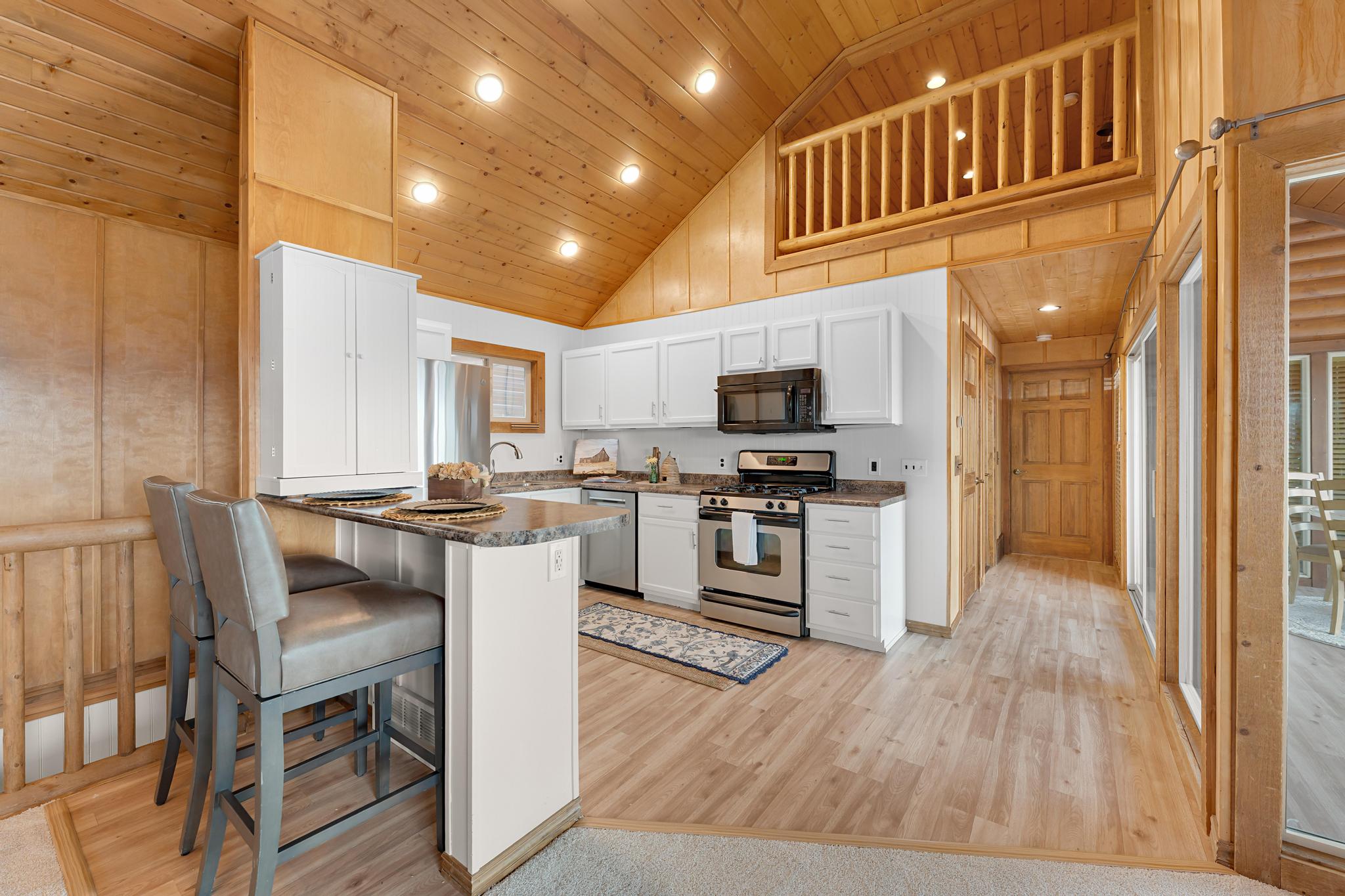 Kitchen featuring recessed lighting, dark countertops, stainless steel appliances, white cabinetry, and a vaulted wood ceiling