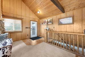 Carpeted foyer entrance featuring plenty of natural light and a vaulted wood ceiling