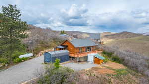 View of front of house featuring a deck with mountain view, log exterior, and an outdoor structure