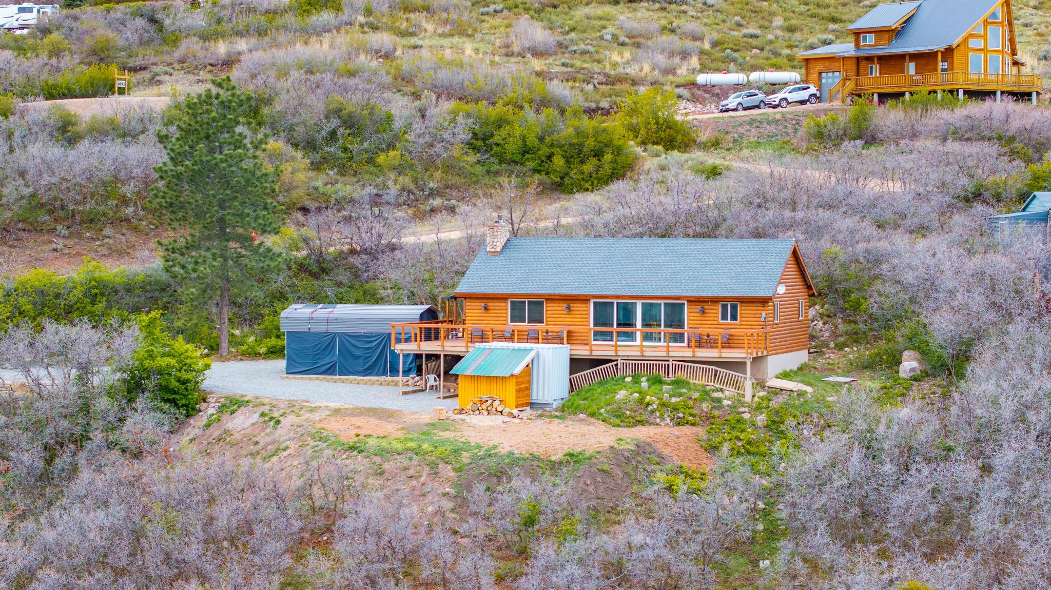 Back of property featuring a wooden deck, log siding, and a chimney