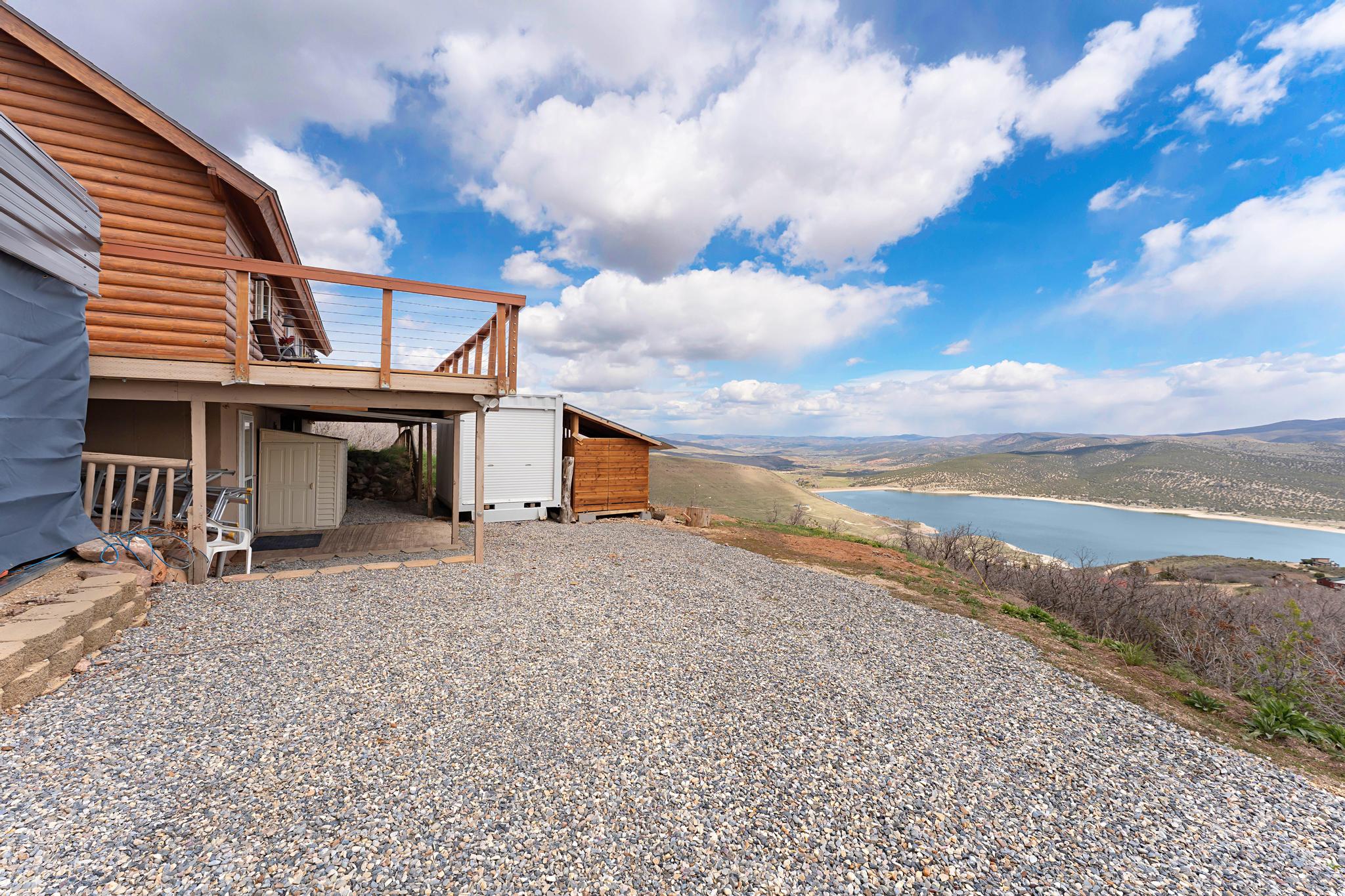View of yard with a deck with water view and an outdoor structure
