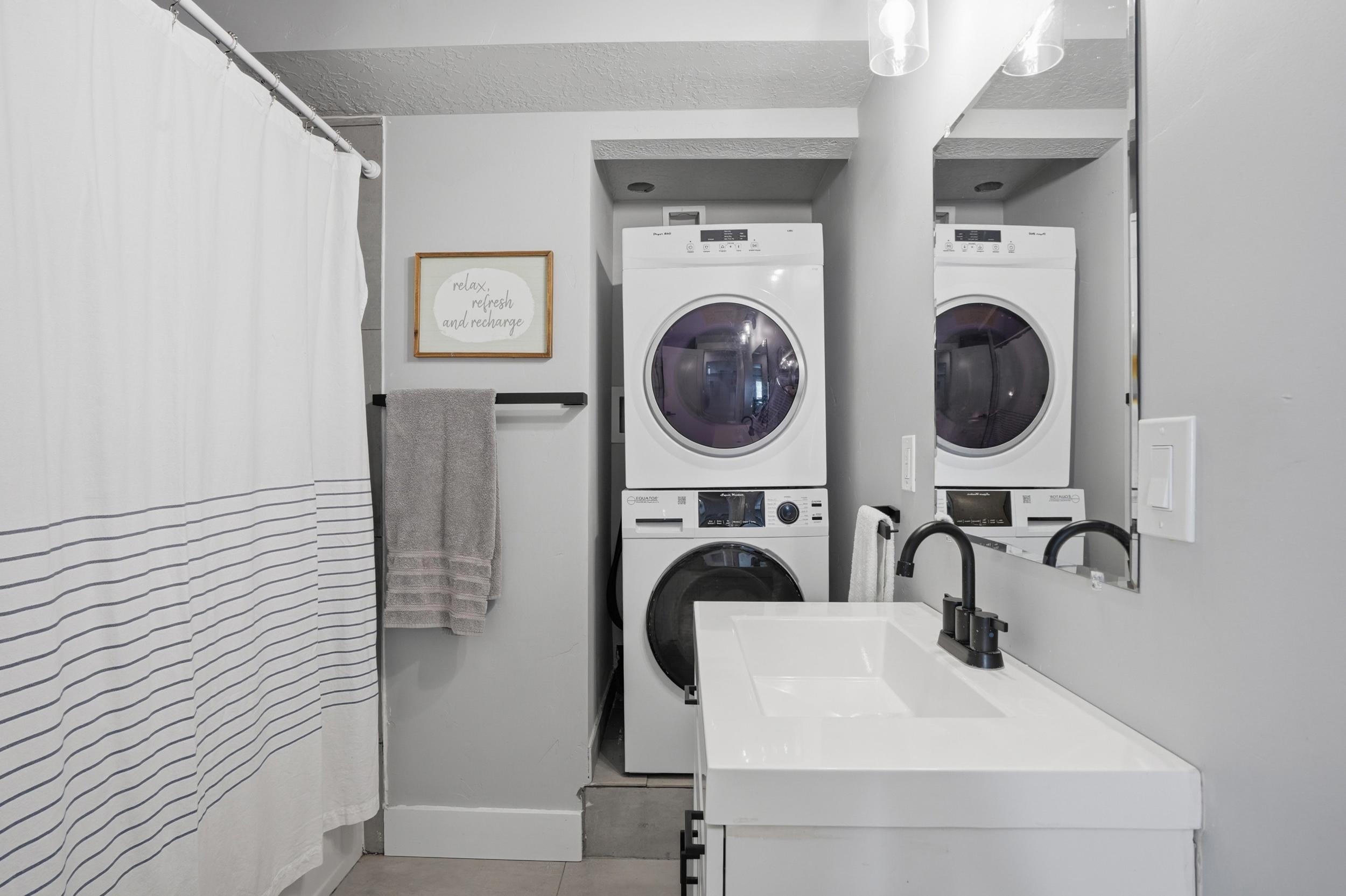 Furnished Unit #44 faces West. Laundry area with stacked washer and clothes dryer and a sink