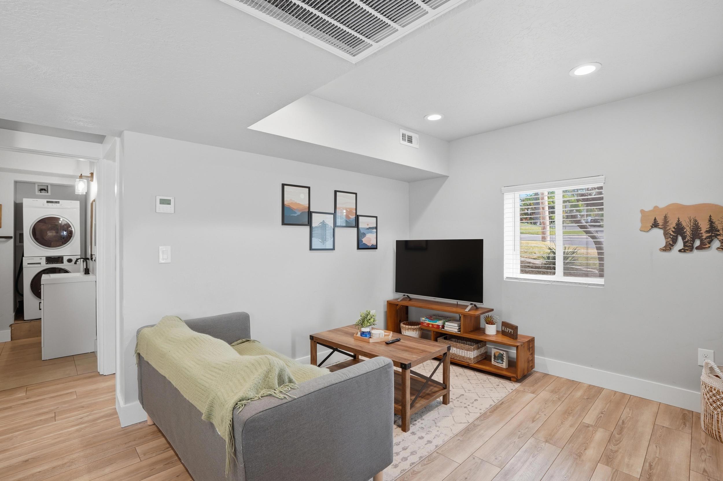 Furnished Unit #44 faces West. Living area with light wood-style flooring, stacked washer / drying machine, and recessed lighting