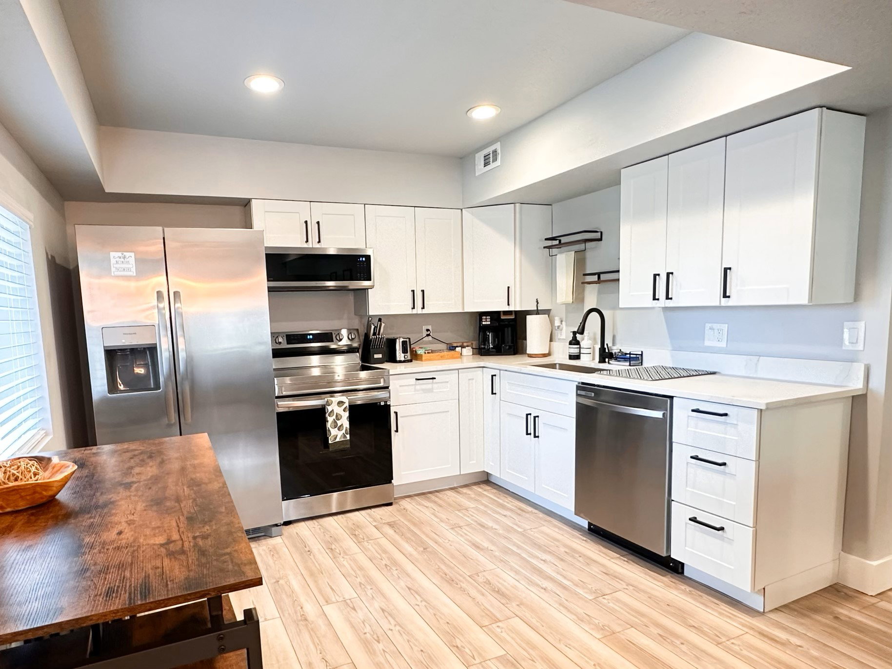 Furnished Unit #44 Kitchen featuring stainless steel appliances, white cabinetry, light wood finished floors, recessed lighting, and dark stone counters