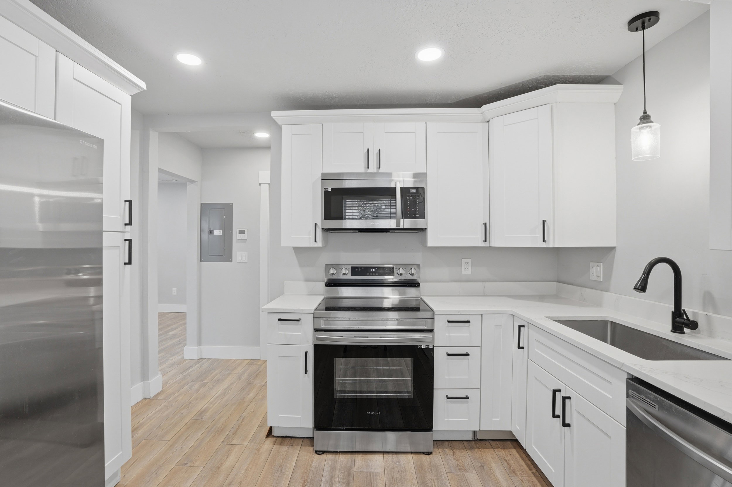 Unit #40 Kitchen with stainless steel appliances, white cabinetry, light stone countertops, and light wood-type flooring