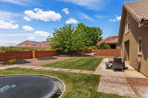 Fenced backyard with a mountain view, a patio, and a trampoline