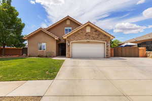 Traditional home with a gate, an attached garage, stucco siding, concrete driveway, and stone siding