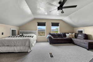Bedroom with a textured ceiling, carpet flooring, and a ceiling fan