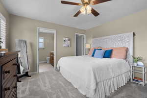 Bedroom featuring light carpet, a ceiling fan, and connected bathroom