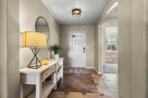 Entryway with inlaid floor details, tile patterned flooring, and arched walkways