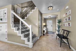 Entrance foyer featuring a textured ceiling, arched walkways, and light tile patterned flooring