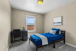 Carpeted bedroom featuring a textured ceiling and an office area