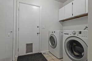Laundry room with cabinet space, light tile patterned floors, and washer and dryer