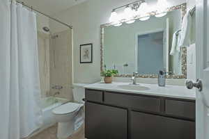 Full bath featuring vanity, shower / bath combo with shower curtain, and light tile patterned floors
