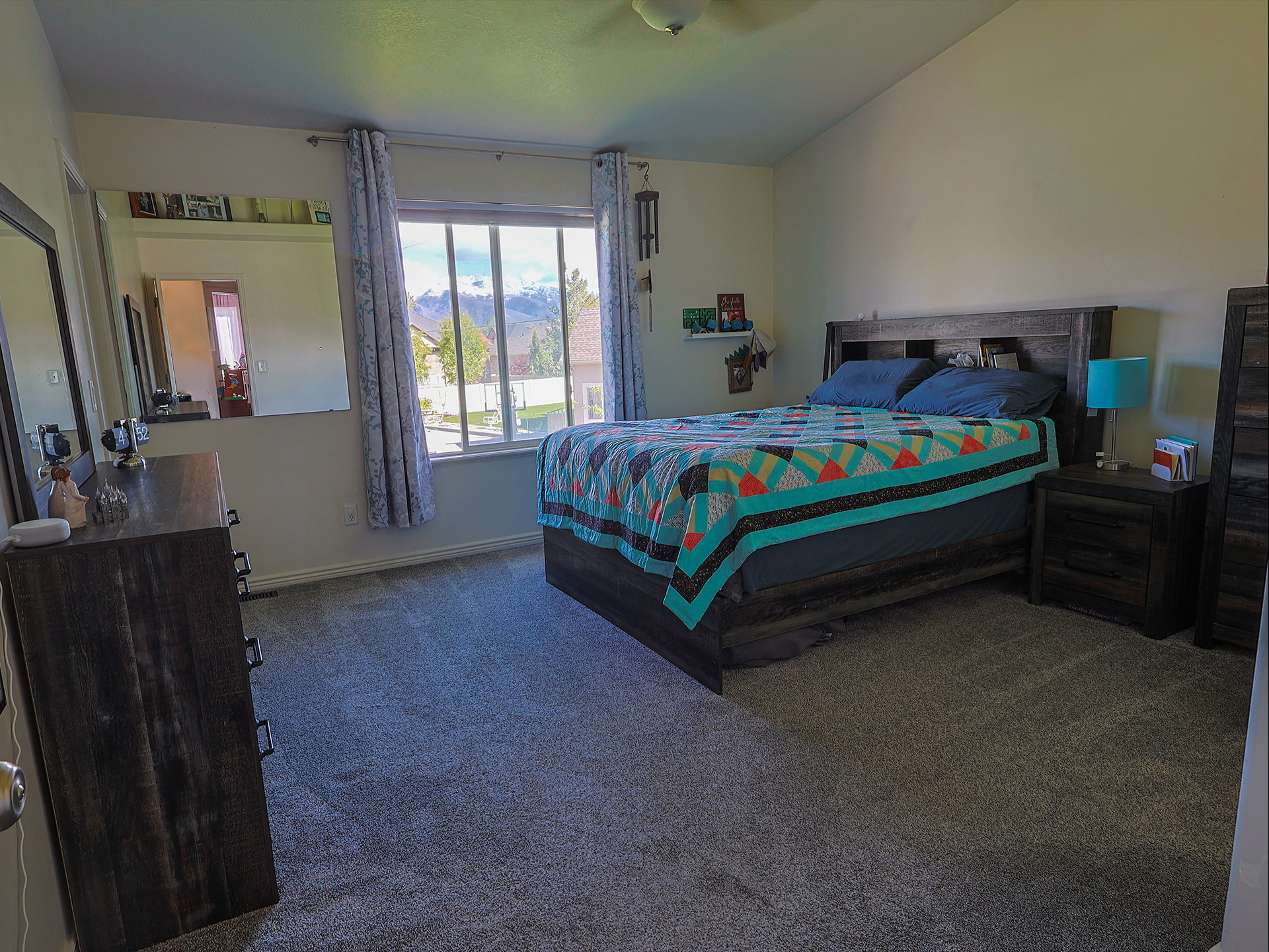 Bedroom with dark colored carpet, lofted ceiling, a mountain view, and a ceiling fan