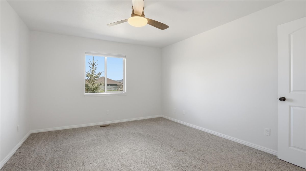 Carpeted spare room featuring baseboards and a ceiling fan