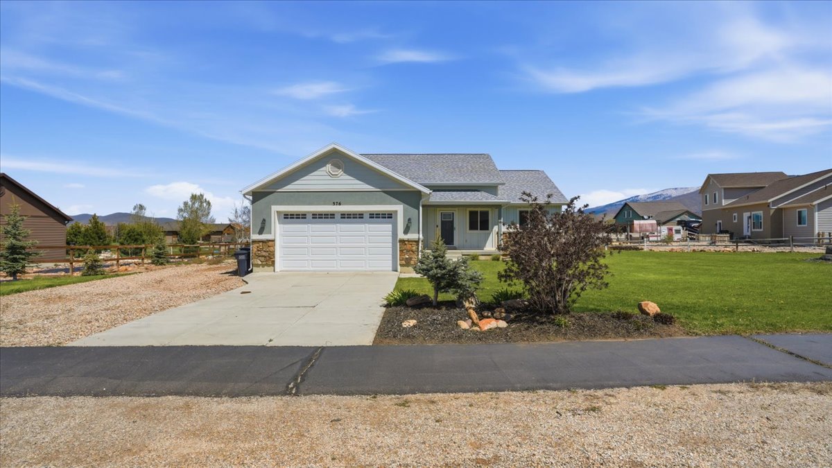 View of front of house featuring a front lawn, driveway, an attached garage, and a mountain view