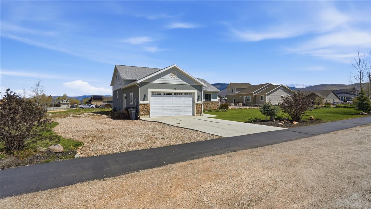 Craftsman-style home with a residential view, driveway, an attached garage, a mountain view, and a front yard