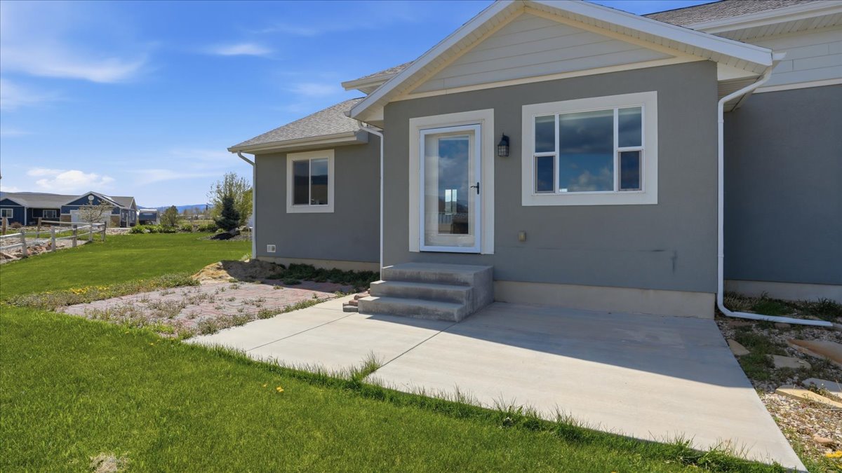 View of front facade with a front lawn, stucco siding, and entry steps