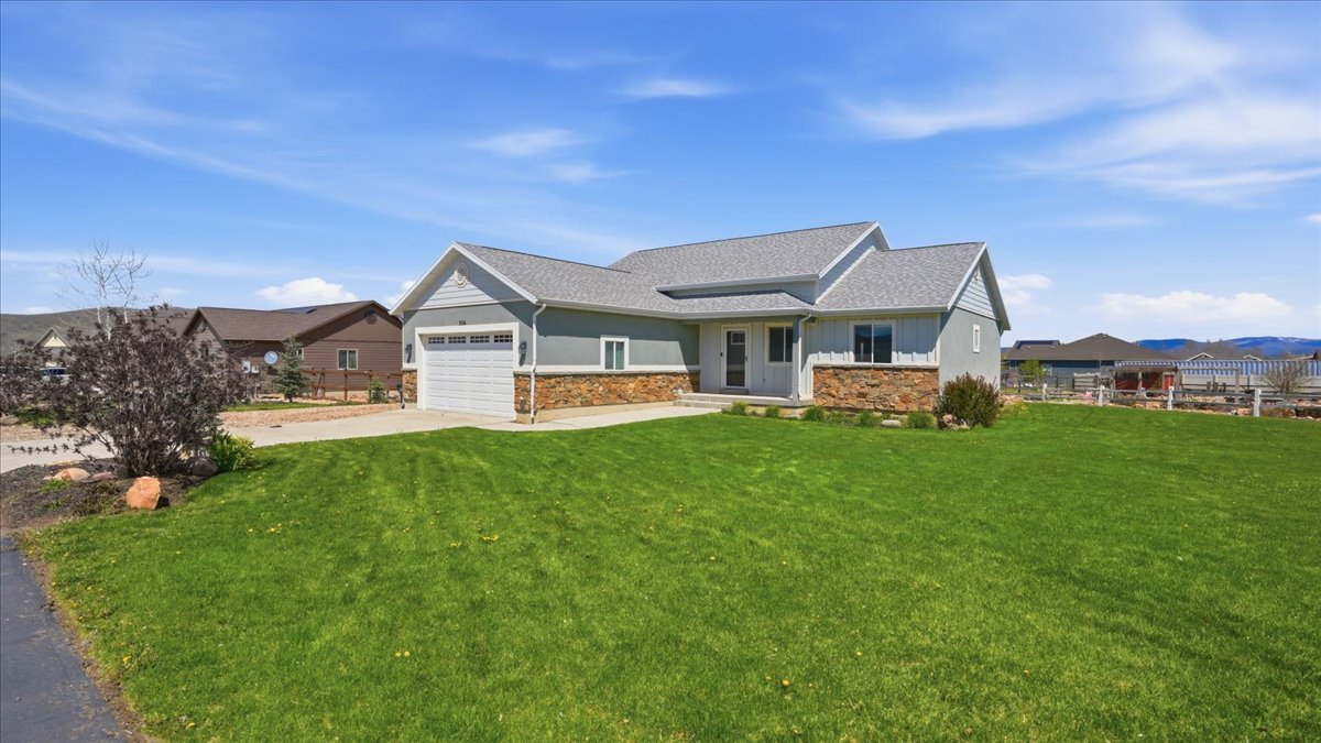 View of front of home with stone siding, a garage, concrete driveway, a shingled roof, and covered porch