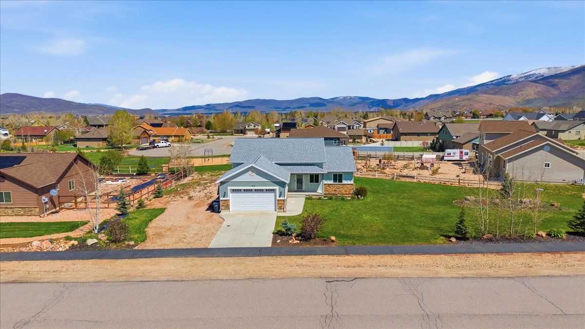 View of front of house featuring a residential view, concrete driveway, an attached garage, and a front yard