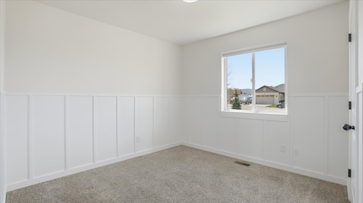 Empty room featuring a decorative wall, a wainscoted wall, and carpet floors