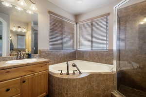 Full bath featuring vanity, a stall shower, and a garden tub