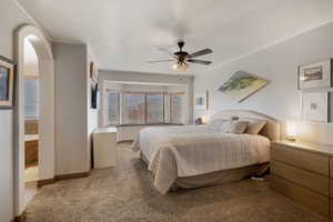 Bedroom with dark carpet, a ceiling fan, and arched walkways