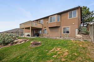 Back of house featuring a fenced backyard, a wooden deck, stucco siding, a fire pit, and a patio area