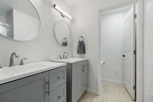 Full bathroom featuring two vanities and light wood-style floors