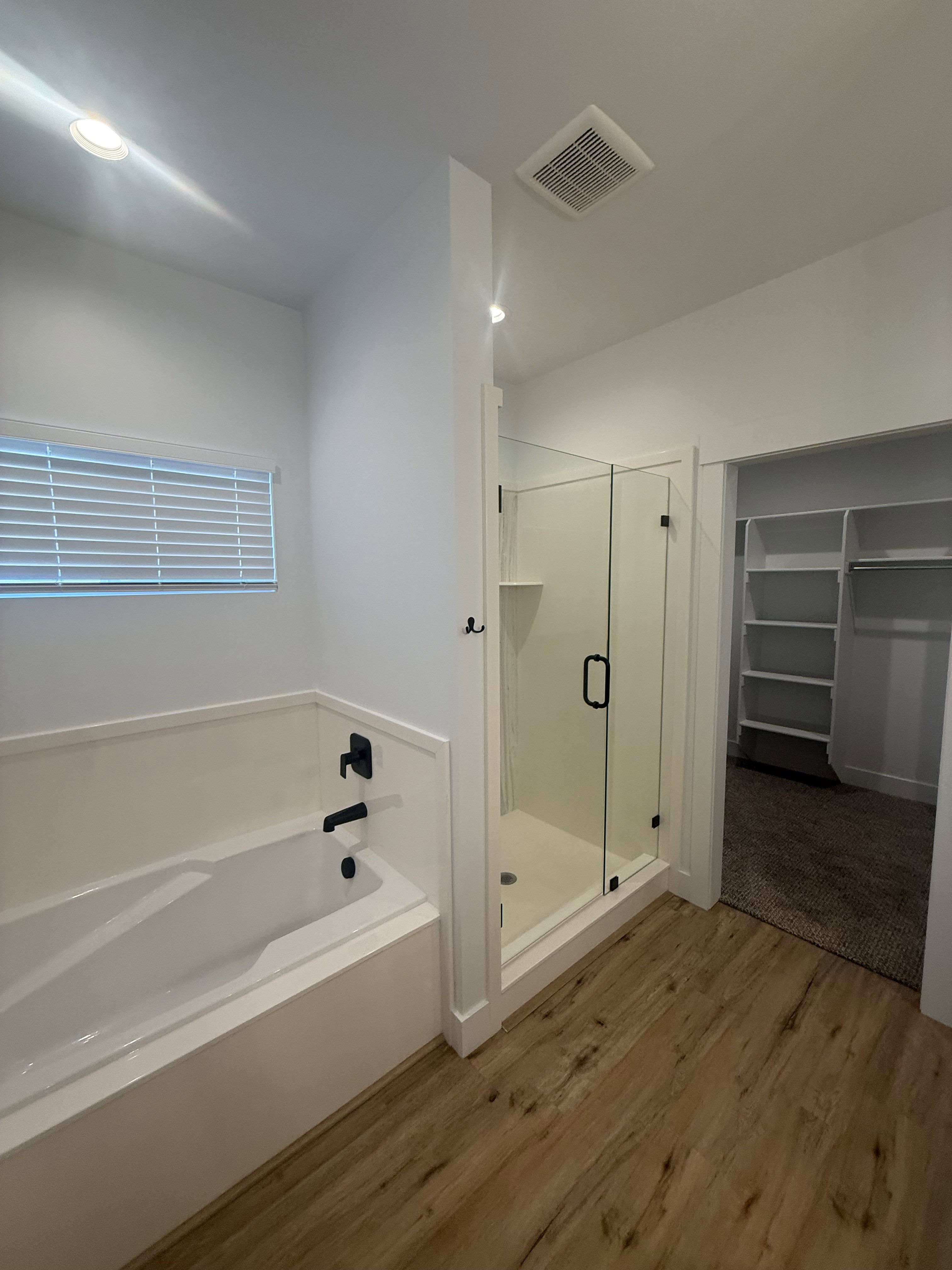 Bathroom featuring a spacious closet, a stall shower, a bath, light wood-style floors, and recessed lighting