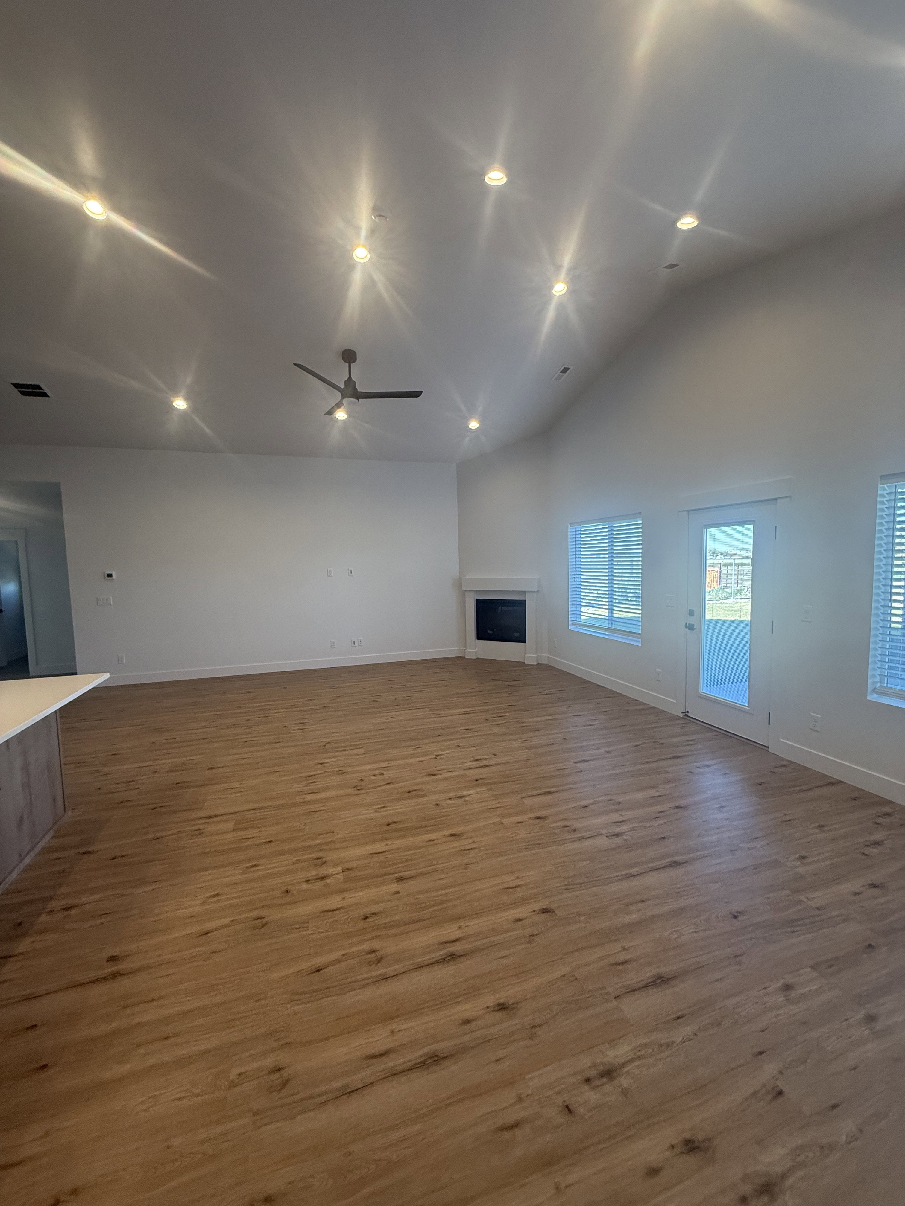 Unfurnished living room featuring a fireplace, light wood-style floors, a ceiling fan, recessed lighting, and lofted ceiling