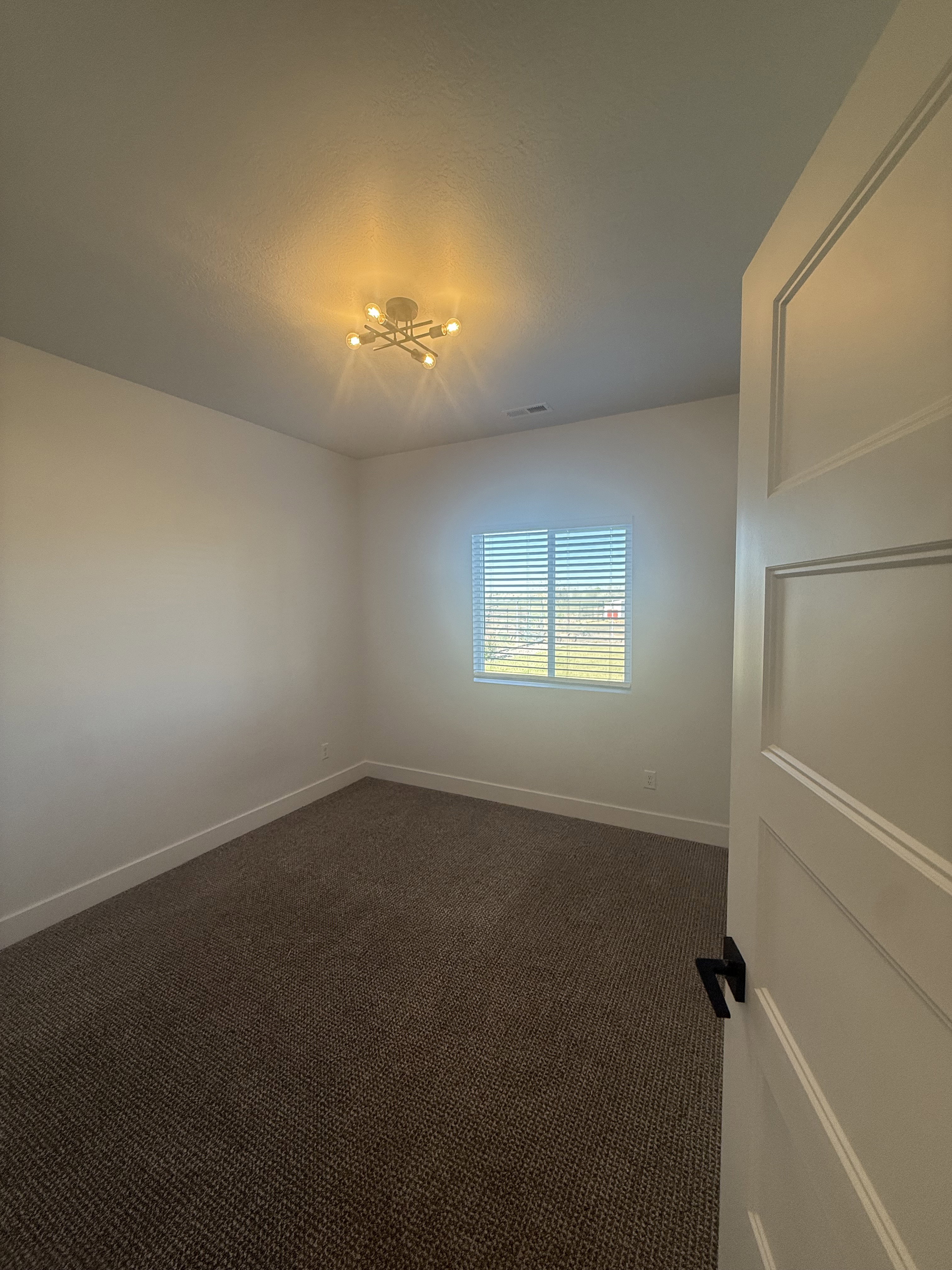 Spare room with dark colored carpet and baseboards