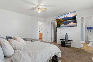 Bedroom featuring ensuite bathroom, light carpet, and ceiling fan
