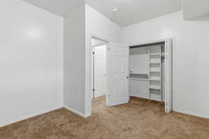 Unfurnished bedroom with a closet, carpet floors, and a textured ceiling