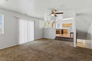 Unfurnished living room featuring ceiling fan, carpet, and a textured ceiling